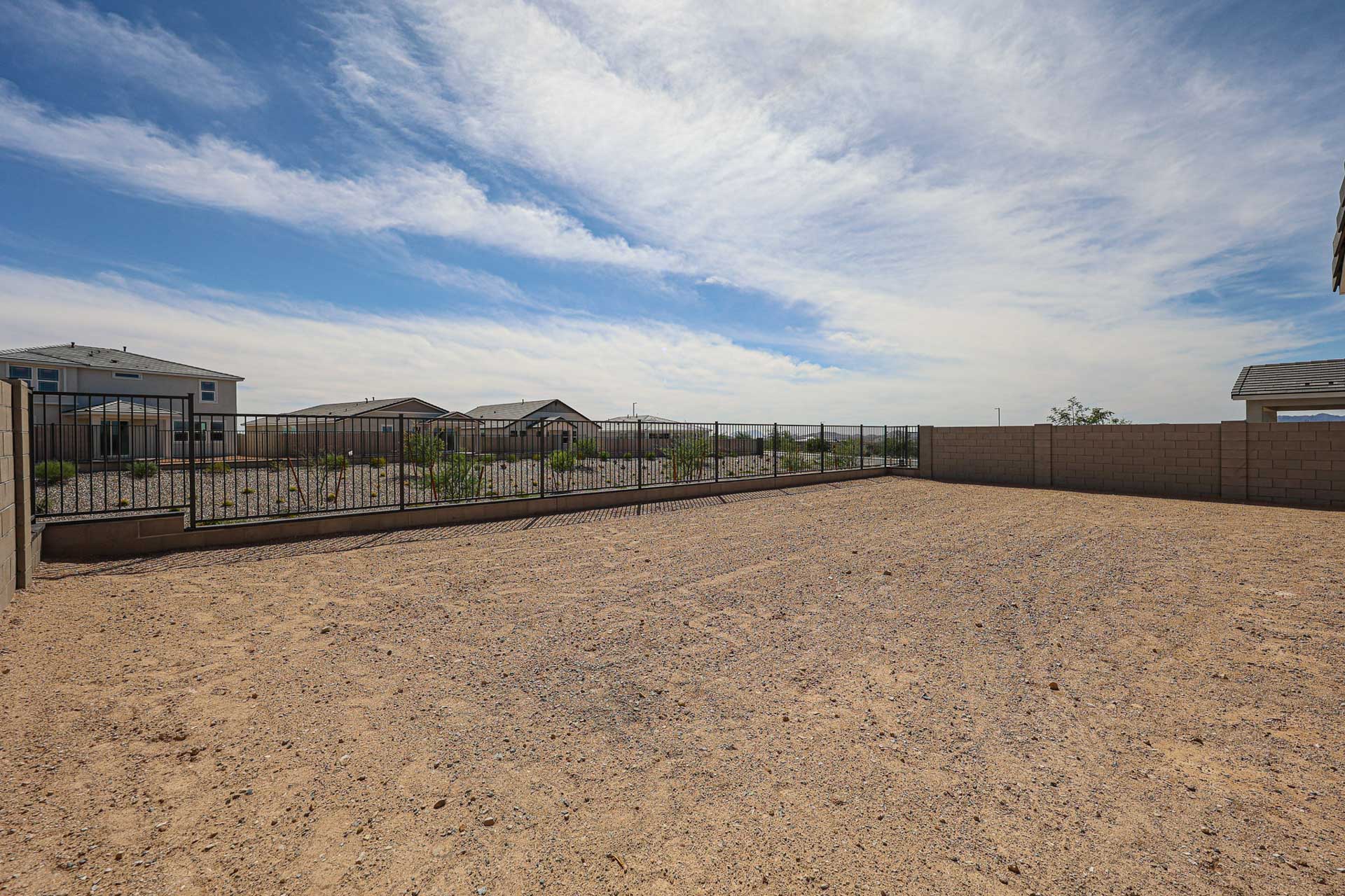 A dirt field with a fence and buildings in the background.