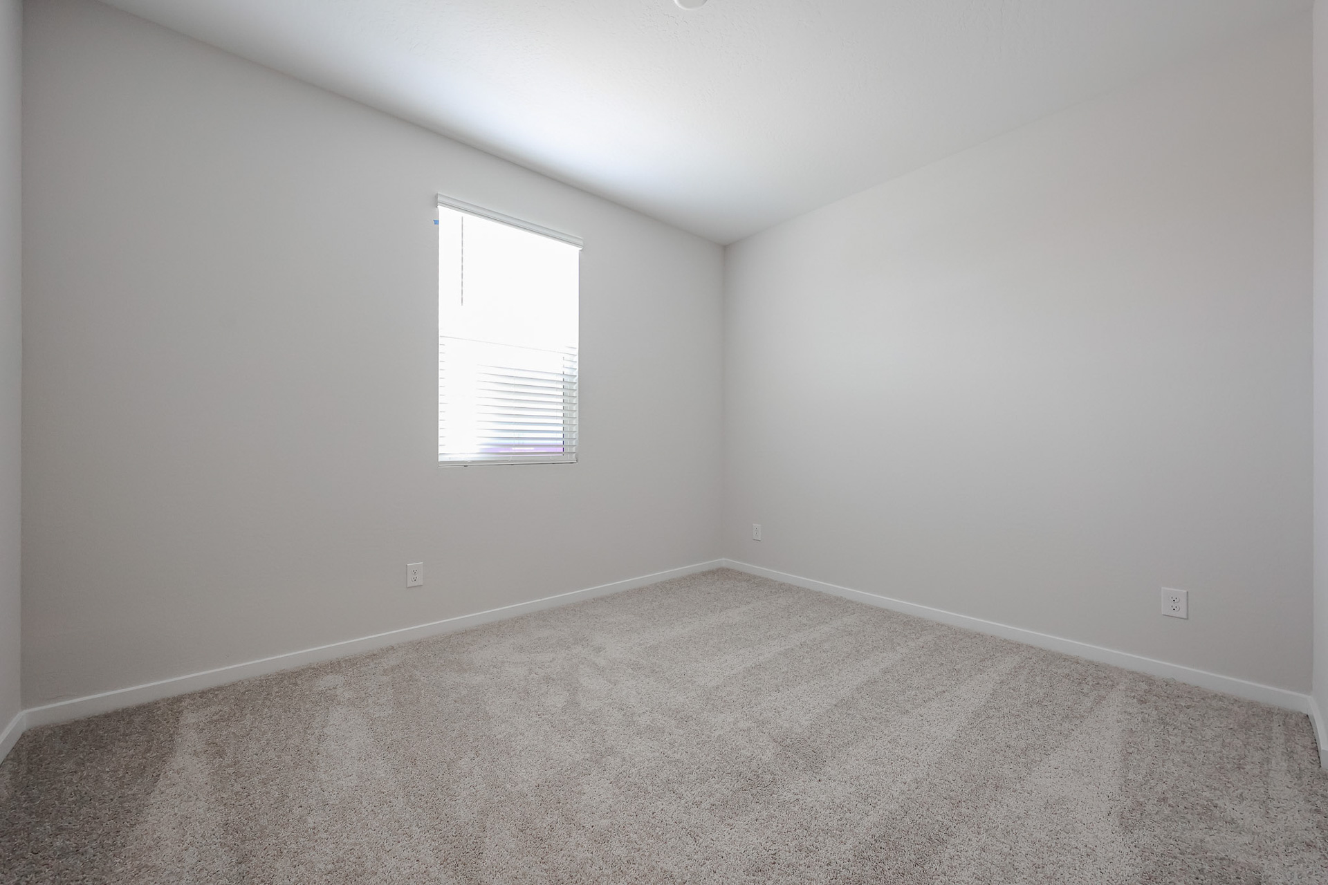 A room with a carpet and a window.