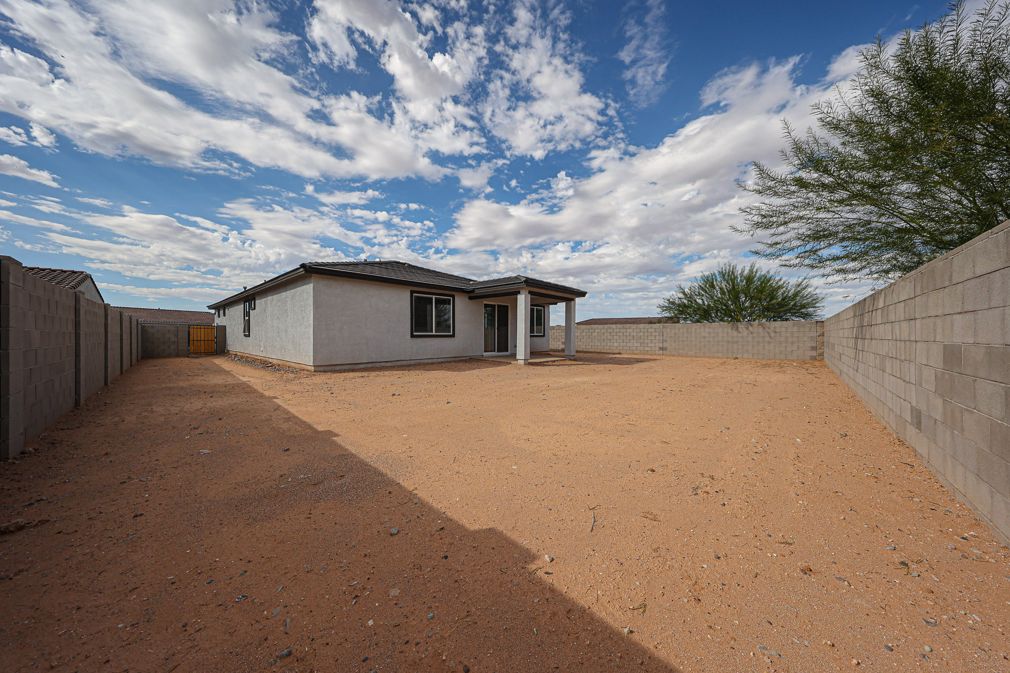 A dirt road with a house on the side.