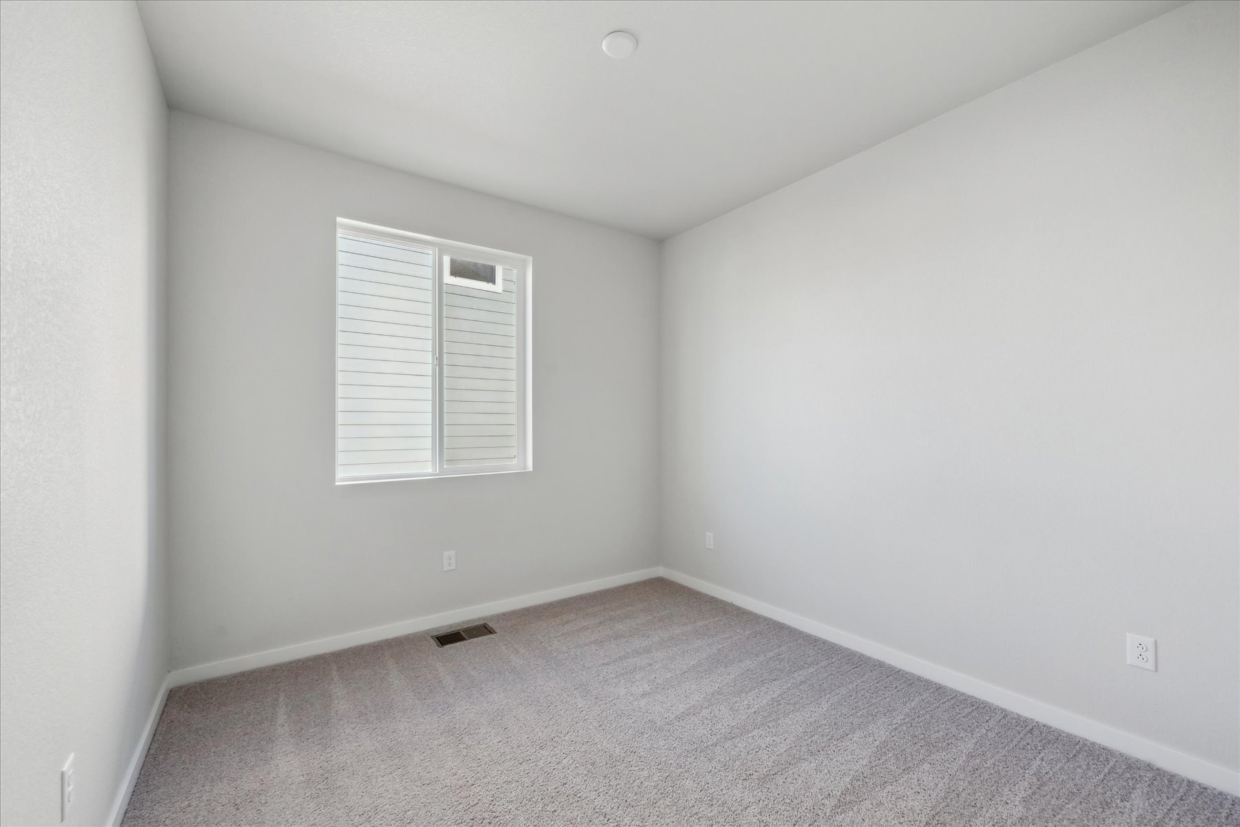 A room with a white wall and a window.