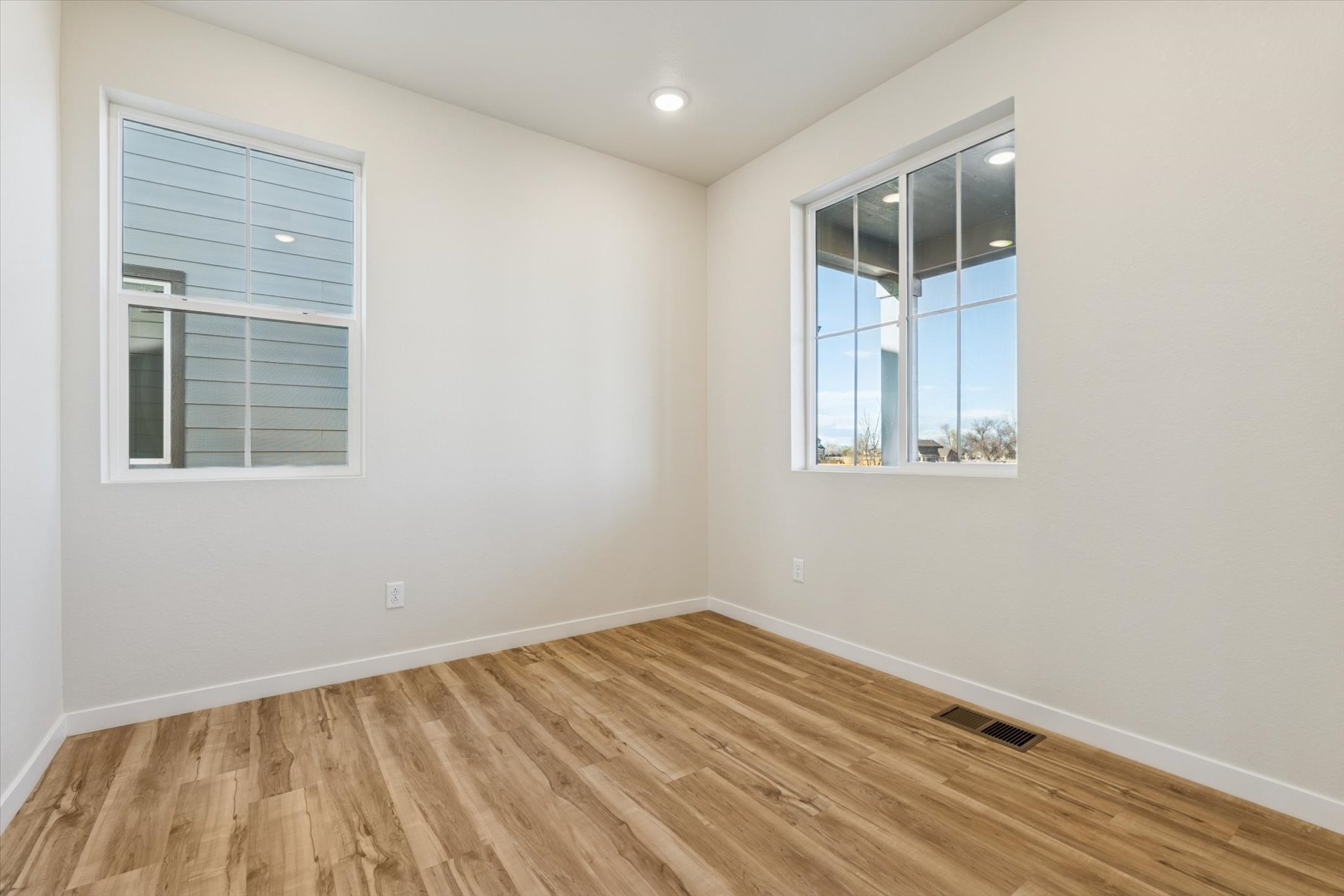 A room with a wood floor and a window with blinds.