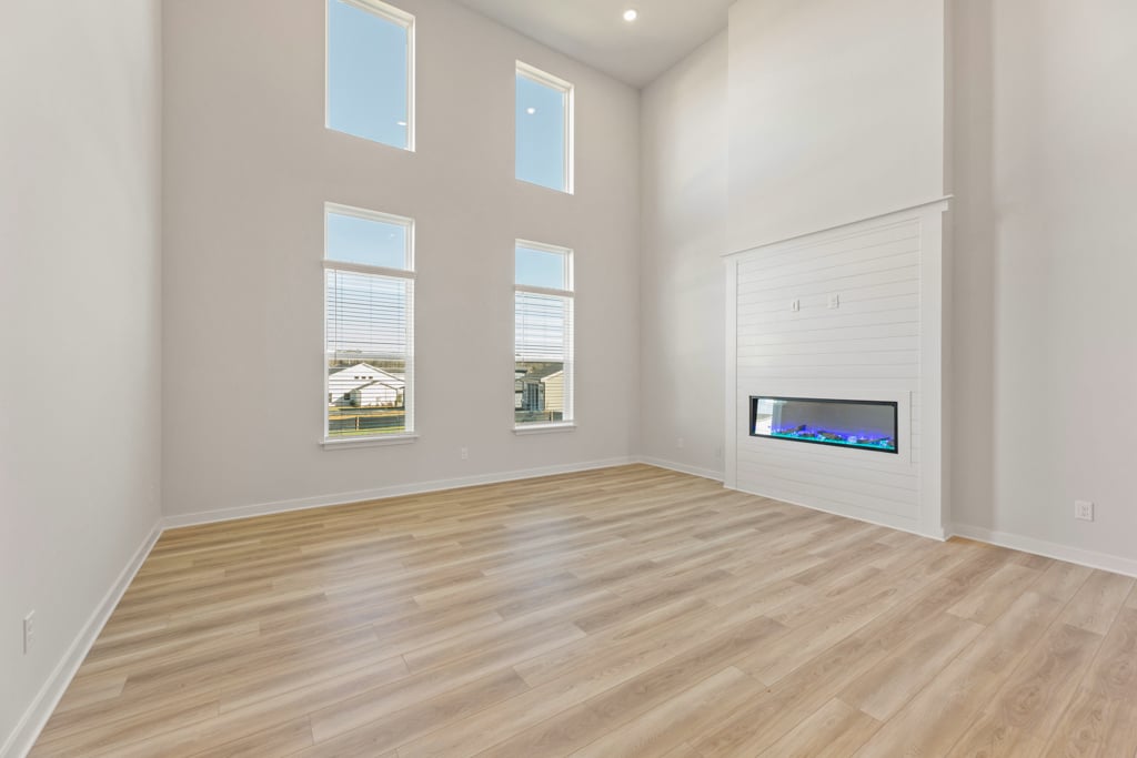 A room with a wood floor and a white wall with a television on it.