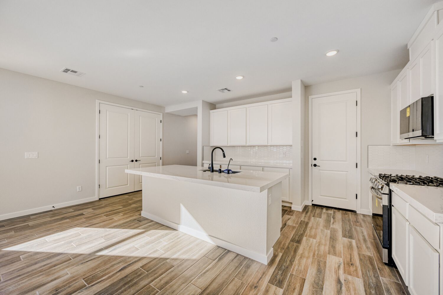 A white kitchen with a tub and white cabinets.