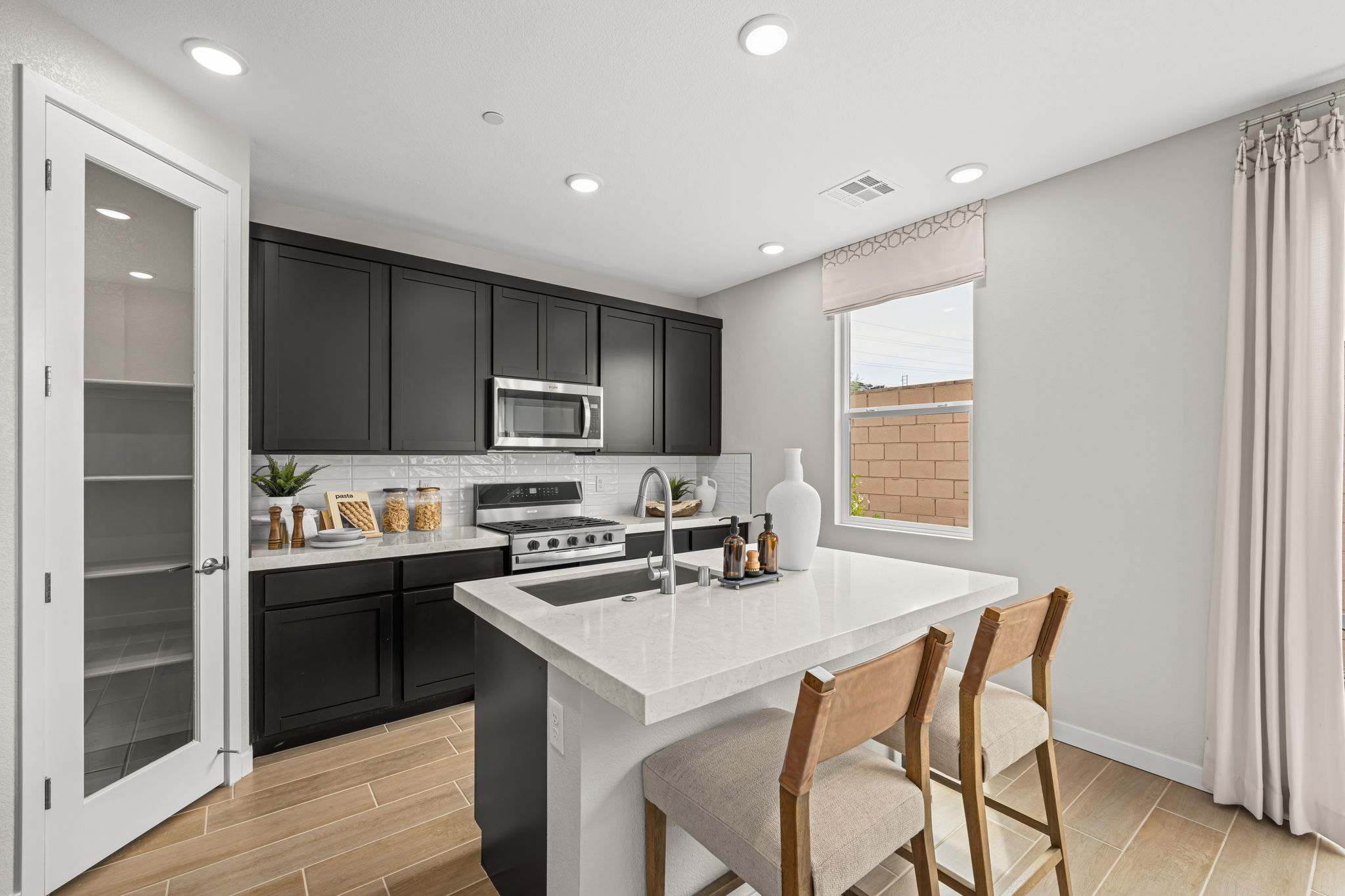 A kitchen with a white counter top and black cabinets.