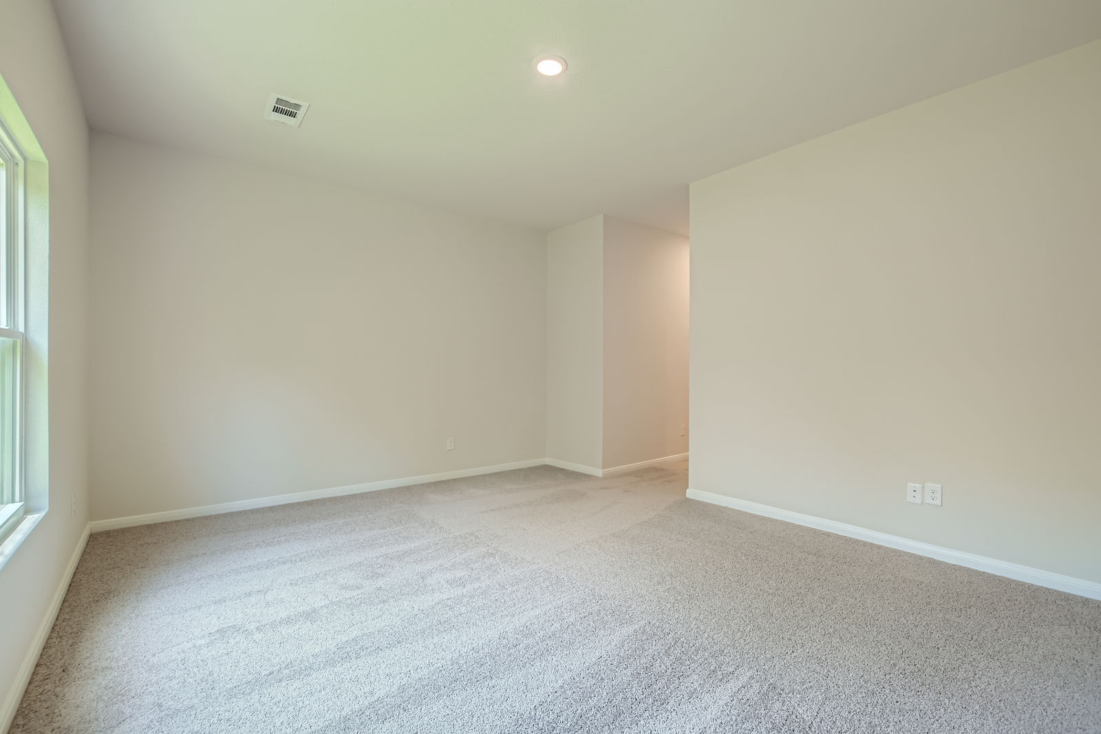 A room with a carpet and a light on the wall.