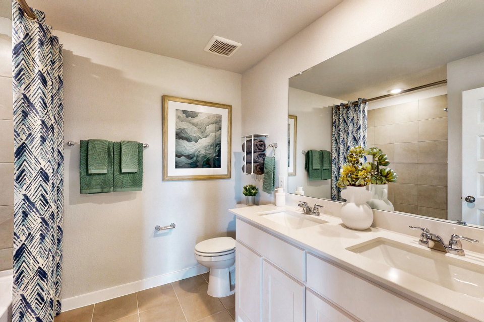 A bathroom with a sink toilet and a mirror.