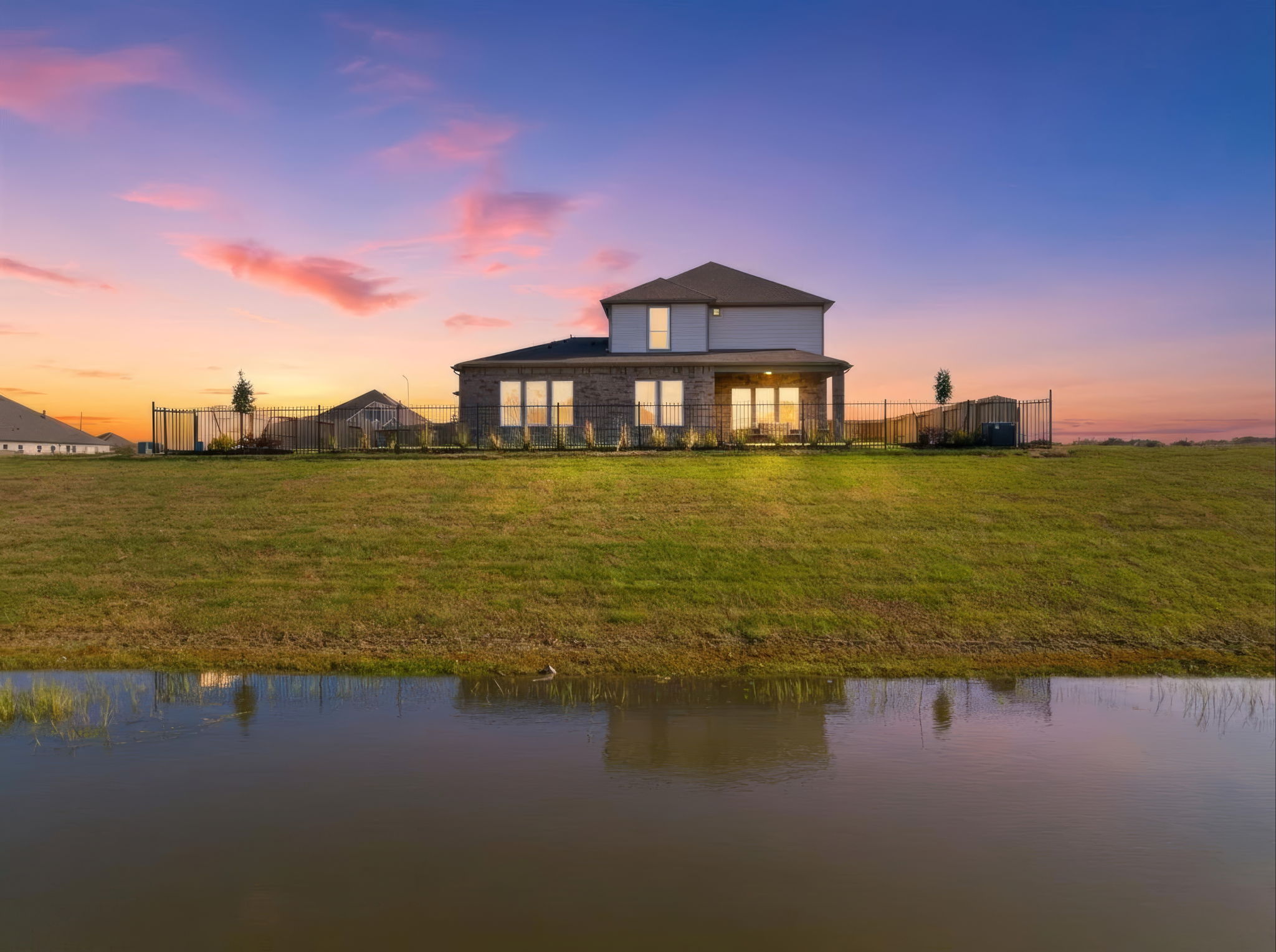 A house with a pond in front of it.