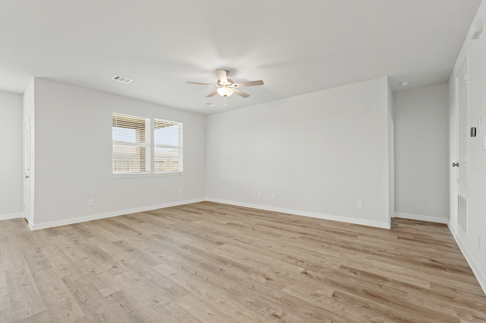 A room with a wood floor and a ceiling fan.