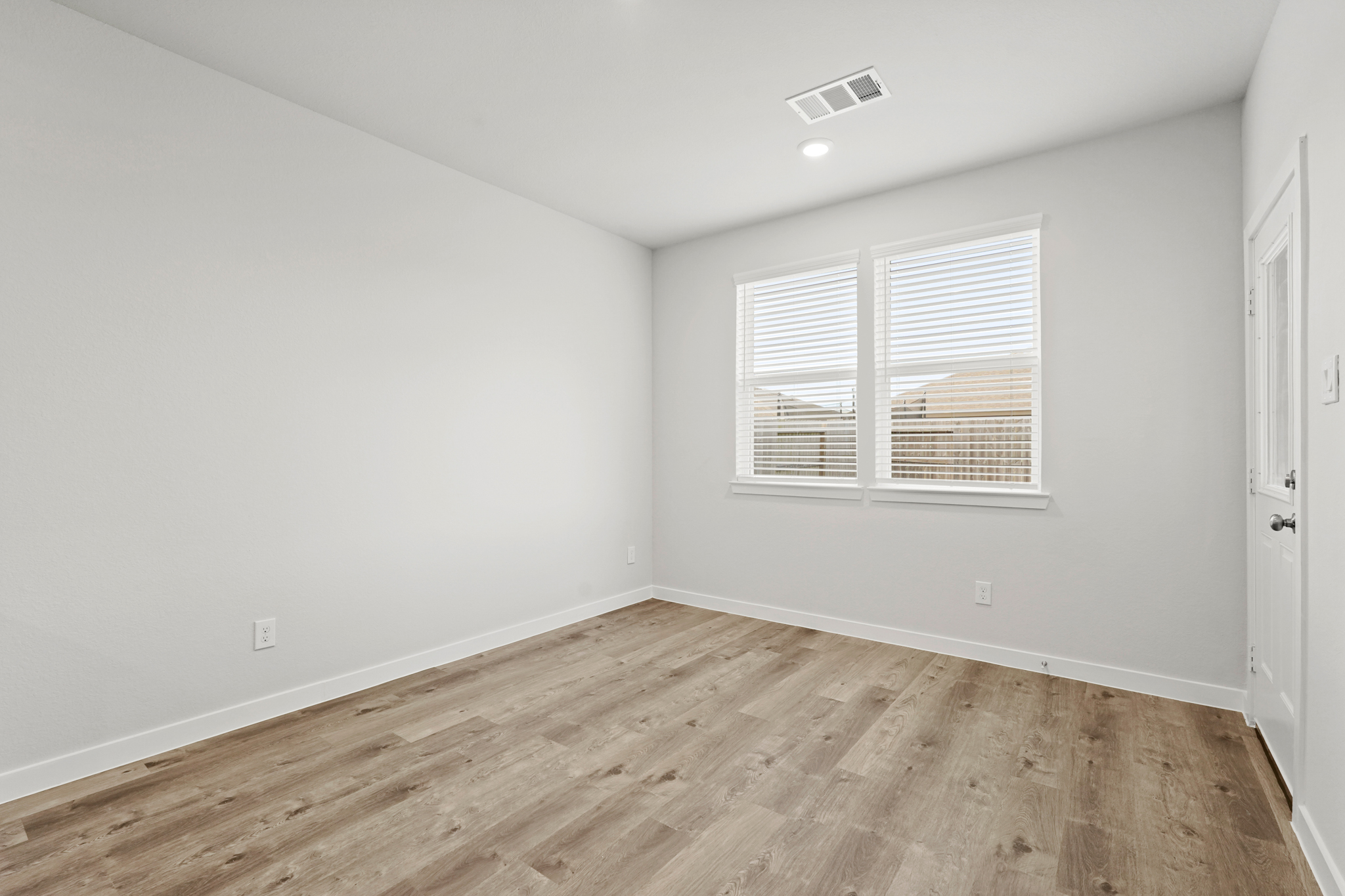 A room with a wood floor and windows.