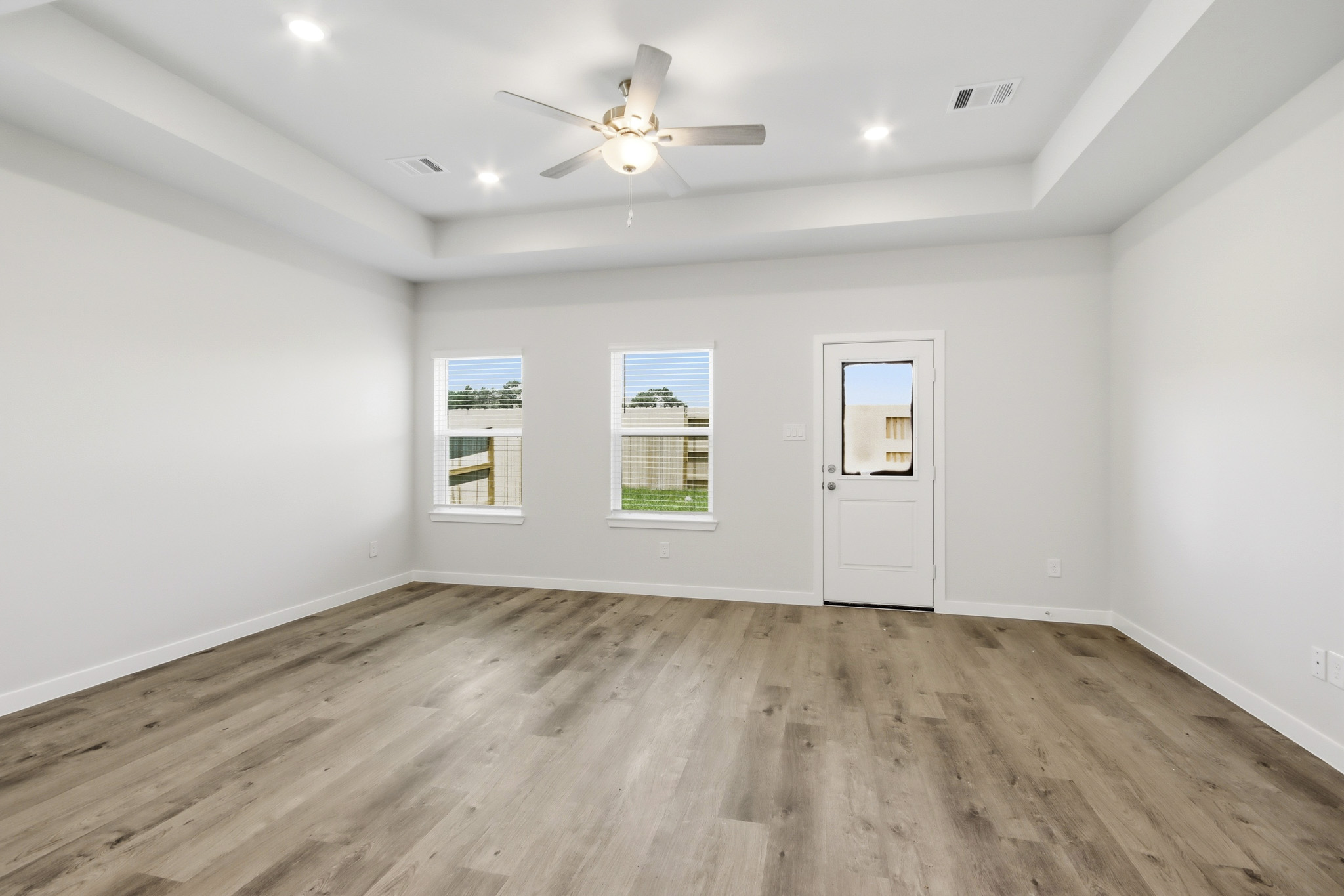 A room with a ceiling fan and a wood floor.