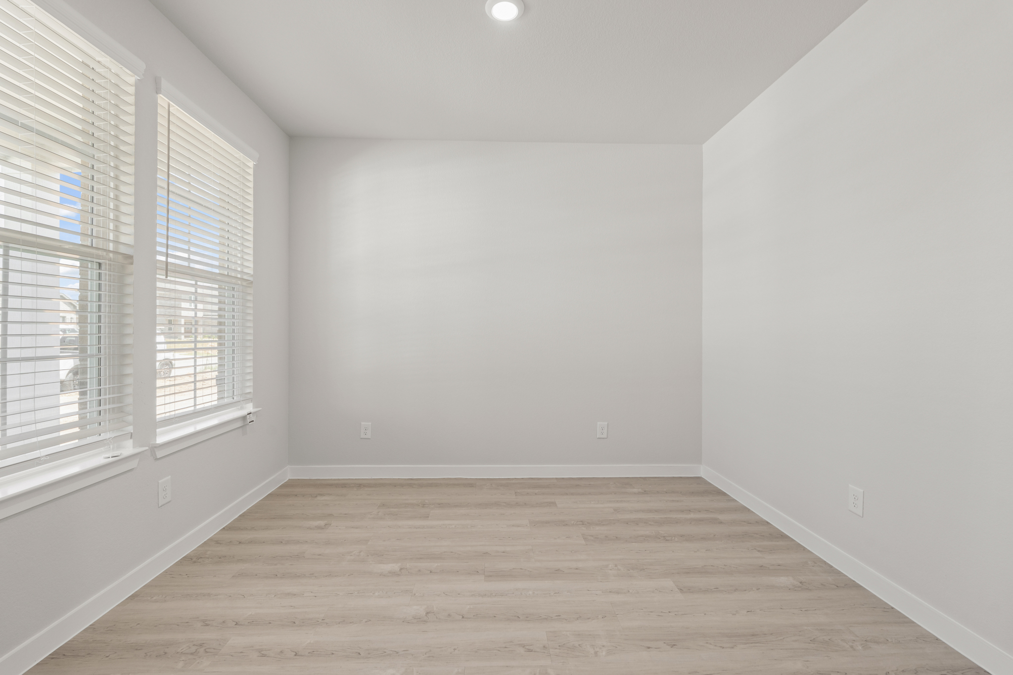 A room with windows and a wood floor.
