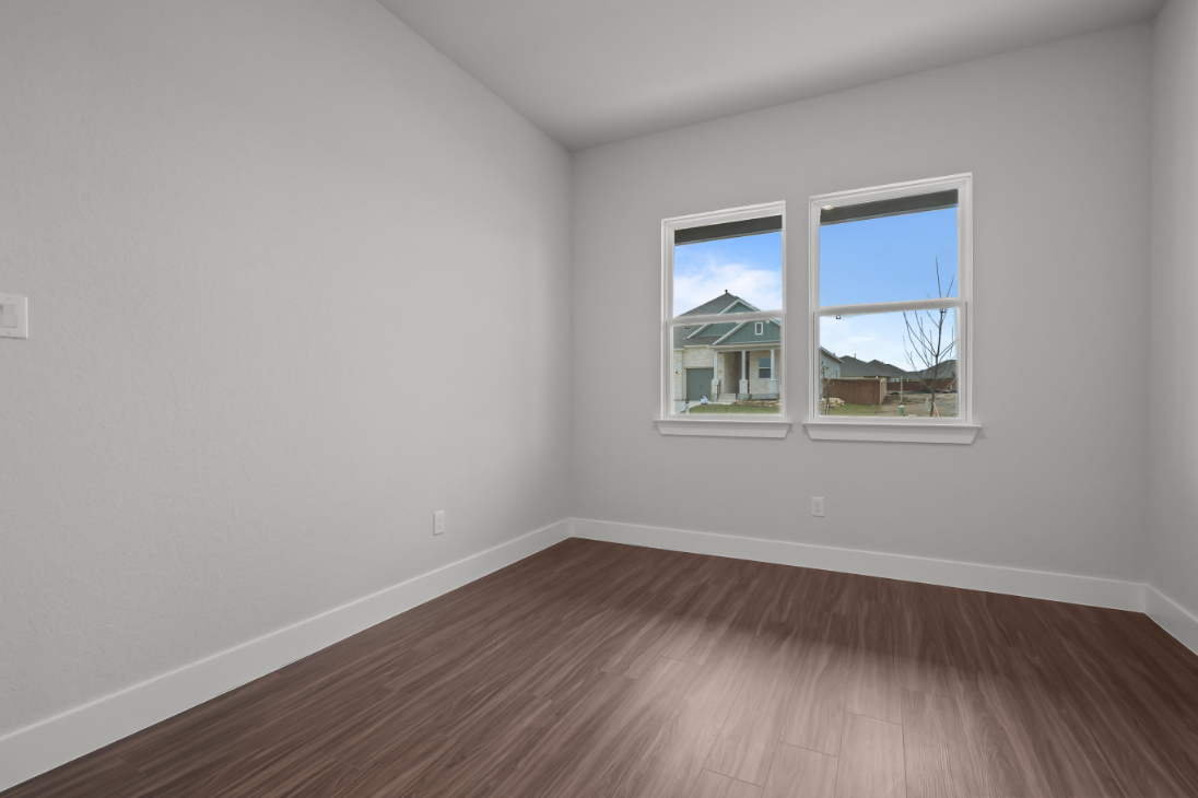 A room with a wood floor and a window with a view of the outside.