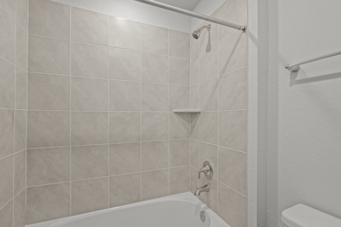 A shower with a tile wall.