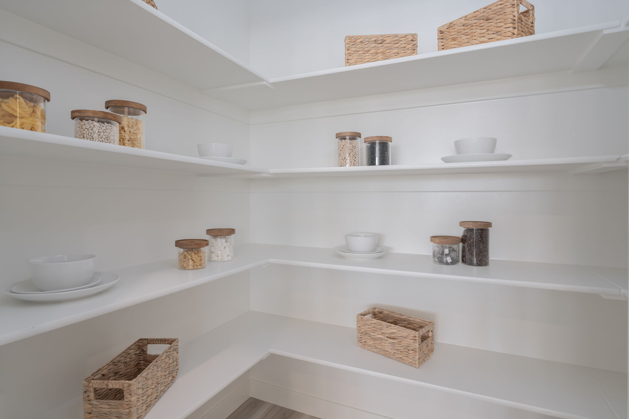 A white shelf with baskets and bowls.