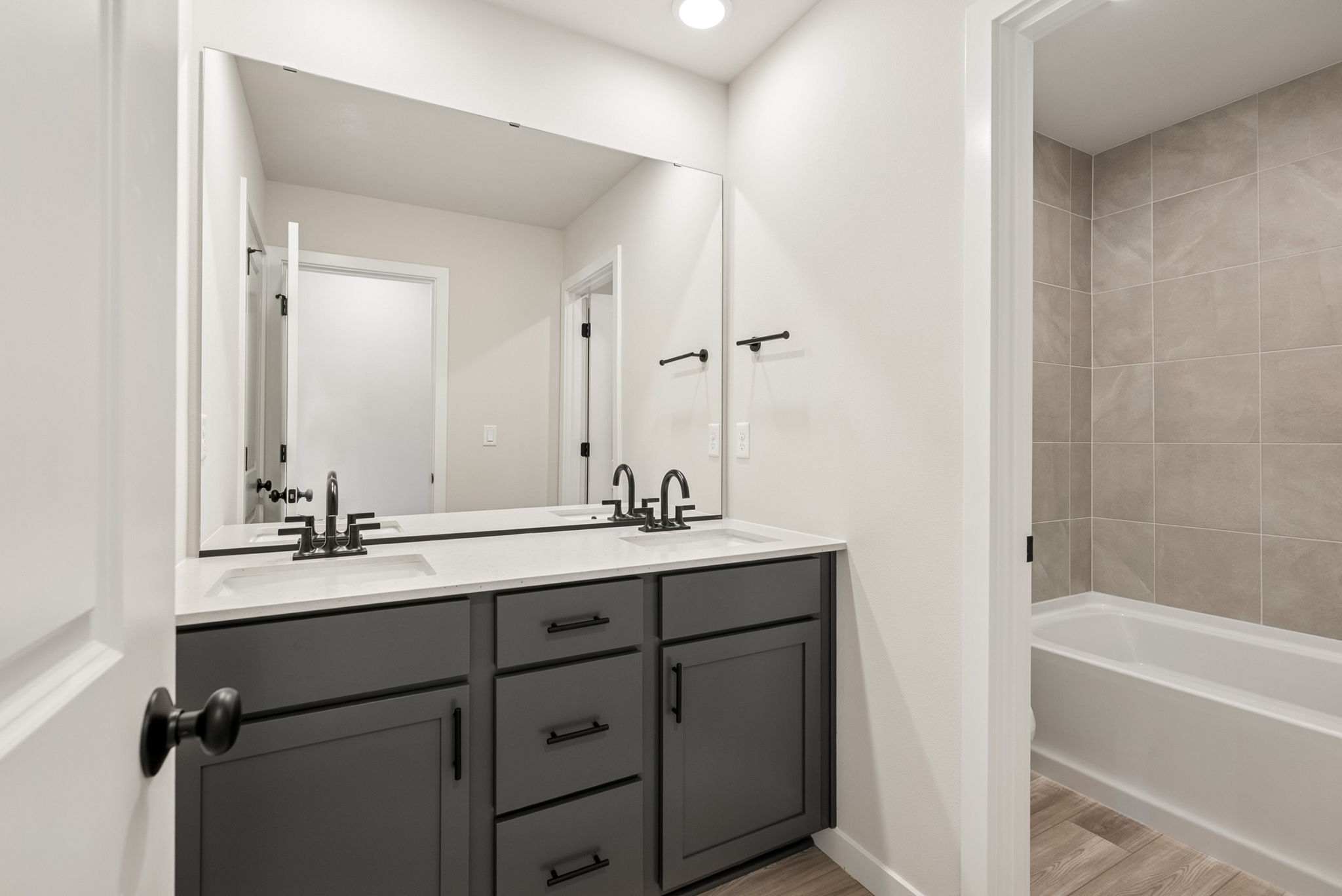 A bathroom with a tub sink and mirror.