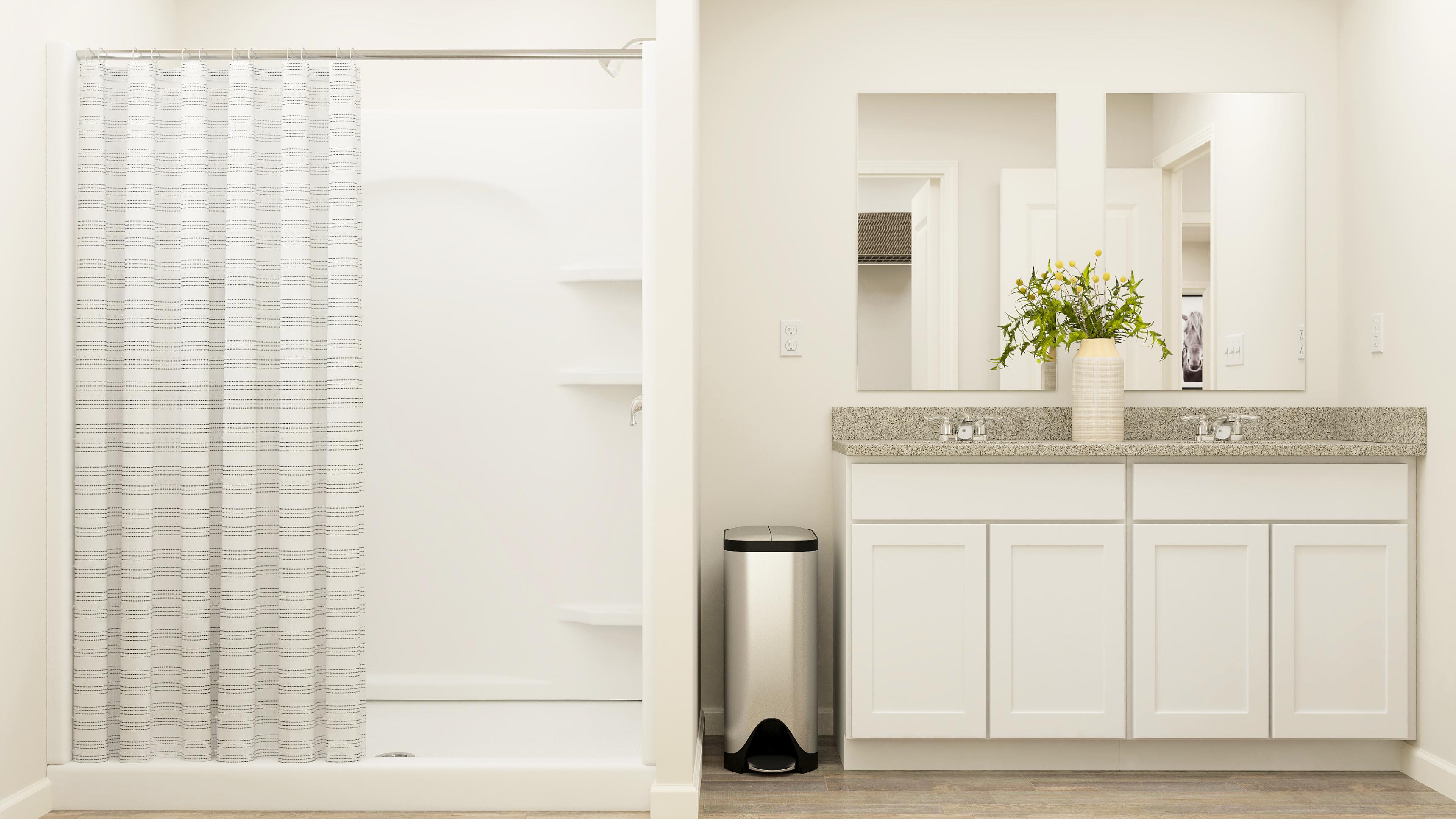 A white kitchen with a black trash can and a white cabinet.